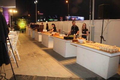 אירוע חיצוני בלילה עם שולחנות אוכל, צוות מגיש אוכל וריהוט לבן להשכרה.