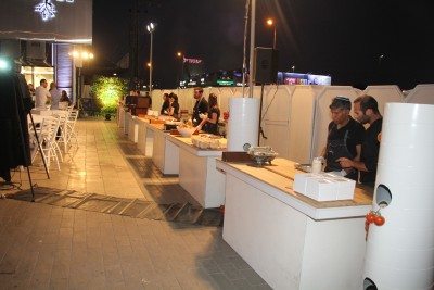 אירוע חוץ עם שולחנות, אנשי צוות וציוד קייטרינג, מתאים להשכרת ציוד לאירועים.