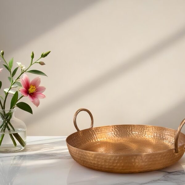 קערת מתכת עם ידיות על שולחן, לצד vase עם פרחים צבעוניים. עיצוב מתאים לאירועים.